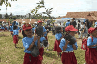 Local schoolchildren carrying young trees