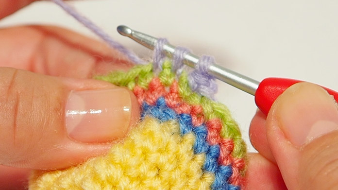 There are 3 loops on the crochet hook. Wrap the wool round the crochet hook and pull through the 3 loops.