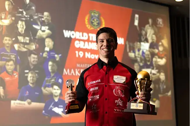Photo of Juan Cruz Lunad Rocha smiling while holding a trophy in each hand