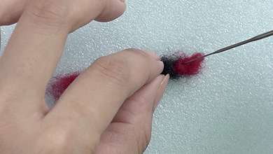 同様に反対側も赤い羊毛をねじり、ニードルで刺していく ワイヤーが見えてしまう場合は、羊毛を足して刺す