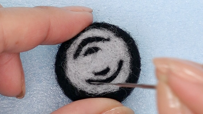 型紙を参考に　少しこよった黒い羊毛で前輪・後輪に模様を刺繍する
