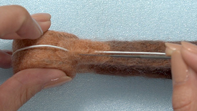 指でワイヤーを押さえながら、ベースと同じ色の羊毛で刺していく