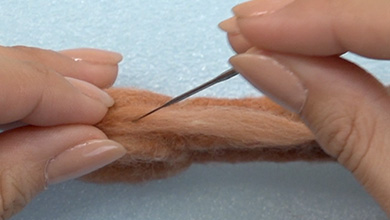 ベースと同じ色の羊毛を細くねじり、側面の中央に刺し付ける