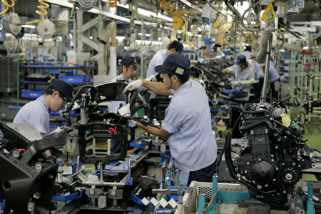 Assembly line technicians mounting completed engines (right) on chassis frames